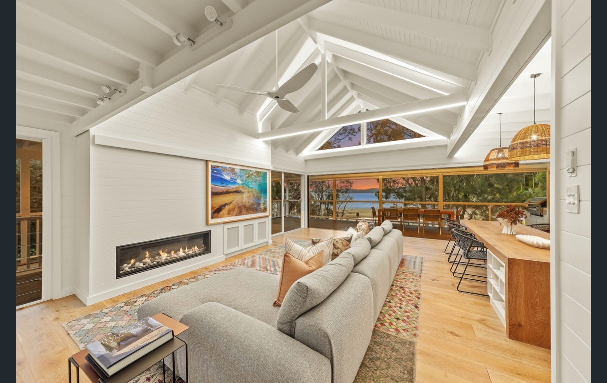 Upstairs living room with vaulted white ceilings, fireplace, and a view through to the water at dusk